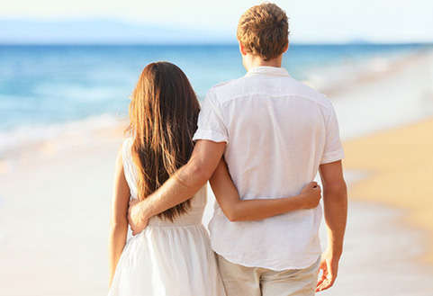 情侣相互抱着腰漫步在海边